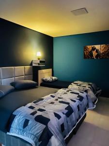 a bedroom with a bed and a blue wall at Pousada Reserva Verde com piscina privada com vista para a serra Studio térreo in Quatro Barras +26 photos
