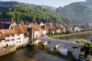 a bridge over a river in a town with houses at maison102 studio Saint-Ursanne Jura in Saint-Ursanne +2 photos