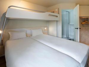 a large white bed in a small room at ibis budget Rennes Chantepie - Hôtel rénové in Chantepie +48 photos