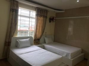 two beds in a room with a window at Queenie Hotel 2 in Hai Phong