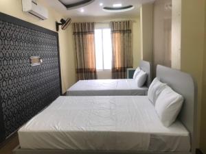 a bedroom with two beds and a window at Queenie Hotel 2 in Hai Phong