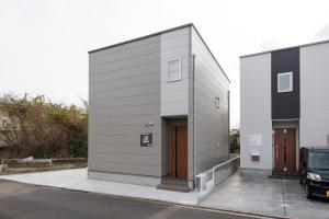 a gray building with a brown door on a street at 巡り宿丸亀-最大9名 in Marugame