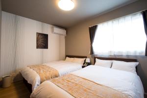 two beds in a room with a window at 巡り宿丸亀-最大9名 in Marugame