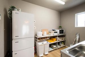 a kitchen with a white refrigerator next to a sink at 巡り宿丸亀-最大9名 in Marugame