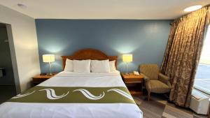 a hotel room with a bed and a chair at Regency Inn in Chickasha