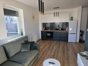 a living room with a couch and a kitchen at Apartament Podmiejska Nova in Kalisz