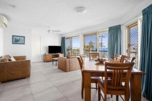a living room with a table and chairs at Kings Way Apartments in Caloundra