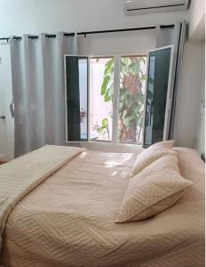 a bedroom with a large bed with two windows at Casa Tamarindo in San Carlos