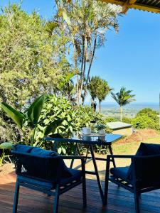 a table and chairs on a deck with a view of the ocean at Cape Byron Cabin in Coorabell Creek