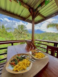 two plates of food sitting on a wooden table at Forest Side Bungalow in Tetebatu