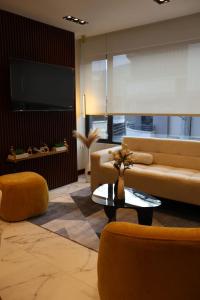 a living room with a couch and chairs and a tv at Ramon Luxury Suites in Gualaceo