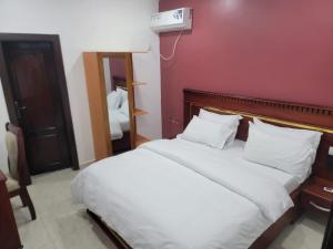 ein Schlafzimmer mit zwei Betten und einer roten Wand in der Unterkunft Hôtel Semto in Edéa