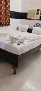 two beds with white sheets and bowls on top at Hotel Kamal in Mumbai