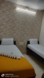 a room with two beds and a brick wall at Hotel Kamal in Mumbai