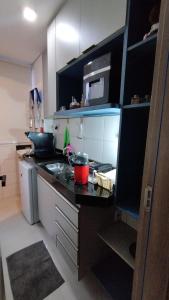 a small kitchen with a stove and a microwave at Studio moderno e bem localizado in João Monlevade