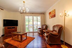 a living room with leather chairs and a flat screen tv at Vila do Conde Nº3 in Ribeira Brava
