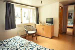a bedroom with a bed and a chair and a television at Beachhouse Isleten in Bauen
