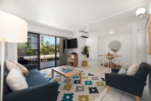 a living room with a blue couch and a table at Joanne Apartments in Caloundra