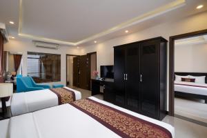 a hotel room with two beds and a television at Banana Garden Hoi An in Hoi An