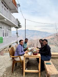 a group of people sitting at a table eating food at Sunrise View Farm-stay -Narkanda in Shimla