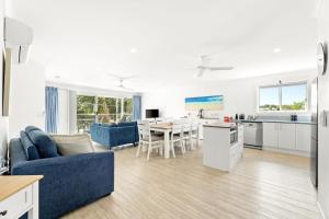 a living room with a blue couch and a kitchen at Unit 8 Boardwalk Apartments in Narooma