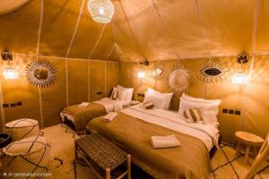 a bedroom with two beds in a tent at Lantern Luxury Camp in Merzouga +27 photos