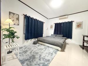 a bedroom with a bed with blue curtains and a rug at RJJhouse Kohphangan in Ban Nua