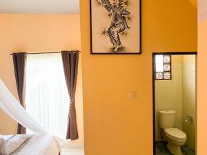 a bathroom with a toilet and a picture on the wall at Geriya Sena in Munduk