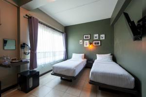 two beds in a room with a window at BB House Rambuttri2 บีบี เฮ้าส์ รามบุตรี2 in Bangkok