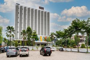 a parking lot with cars parked in front of a building at JP Hotel Pluit Jakarta by LIFE in Jakarta