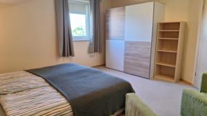 a bedroom with a bed and a cabinet and a window at Sunset Apartment in Grafenwöhr