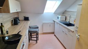 a kitchen with white cabinets and a sink and a stool at Sunset Apartment in Grafenwöhr