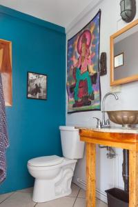a bathroom with a toilet and a painting on the wall at Sweet Spot Stay - Tropical TreeTops Home in Pahoa +22 photos