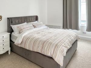 a white bedroom with a bed and a night stand at Thirslet in Maldon