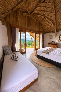 a bedroom with two beds and a large window at Green Poya - Luxury Eco Bambu Resort in South Lombok in Selong Belanak +154 photos