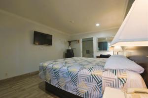 a bedroom with a bed with a tv on the wall at Welcome Inn Corona in Corona