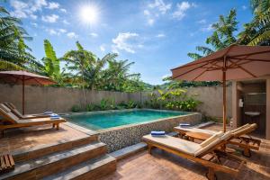 an outdoor pool with two chairs and an umbrella at Grand Kuta Hotel Lombok - Pool - 43 inch Google TV - Strong 60Mbps WiFi - New Enhanced Management in Kuta Lombok