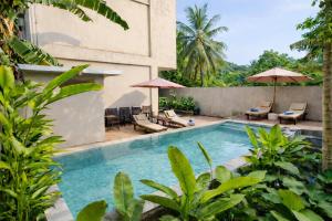 a pool at a resort with chairs and umbrellas at Grand Kuta Hotel Lombok - Pool - 43 inch Google TV - Strong 60Mbps WiFi - New Enhanced Management in Kuta Lombok