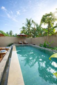 a swimming pool with chairs and an umbrella at Grand Kuta Hotel Lombok - Pool - 43 inch Google TV - Strong 60Mbps WiFi - New Enhanced Management in Kuta Lombok
