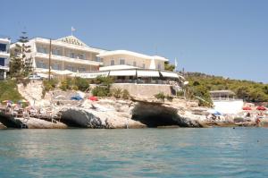 een groot gebouw op een klif naast het water bij Panorama Hotel in Agia Marina Aegina