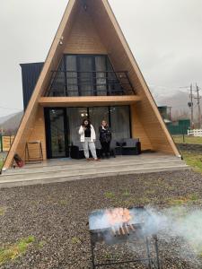 two people standing in front of a house with a fire at WoodCottage in Borjomi
