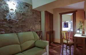 a living room with a green couch and a stone wall at Casa Rural La Chimenea in Navas del Madroño