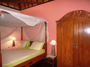 a bedroom with a canopy bed and a cabinet at Saraswati Holiday House in Lovina