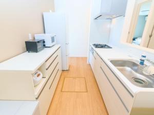 a white kitchen with a sink and a counter at Burikina Terrace in Nago