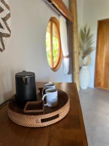 a wooden table with a tray with a cup and a mug at Green Poya - Luxury Eco Bambu Resort in South Lombok in Selong Belanak