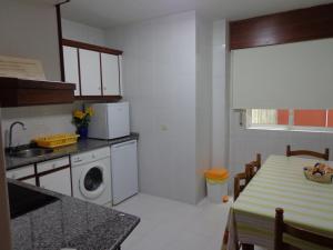 a kitchen with a table and a washing machine in it at Apartamento Milladoiro in Milladoiro