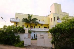 a yellow house with a white fence in front of it at Art cafe in Auroville