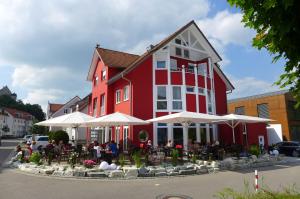 a red and white building with tables and umbrellas at Hotel & Ristorante Passarelli in Warthausen