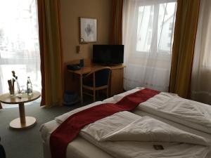 a bedroom with a bed and a desk and a television at Hotel & Ristorante Passarelli in Warthausen