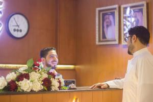 two men standing behind a counter with flowers at شاطئ الحياة للشقق المخدومة in Jeddah